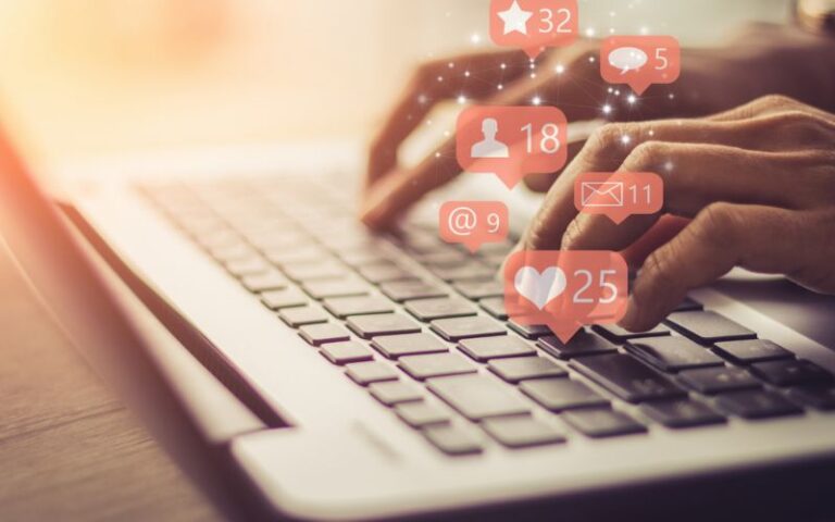 Hands typing on laptop keyboard with social media notifications overlay, representing digital engagement and SEO optimization using modern marketing tools.